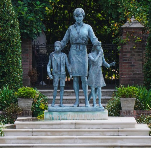 Ian Rank-Broadley's bronze of Diana, Princess of Wales, with three children beside her, standing on its plinth in the Sunken Garden between clipped hedges
