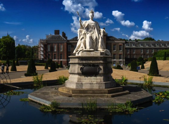 Princess Louise's marble statue of Queen Victoria standing in its basin on the east front of Kensington Palace, the brick ranges running away on both sides